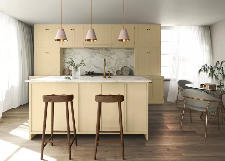 A bright and airy kitchen with cream-colored cabinets, wooden bar stools, pendant lights, and marble countertops.