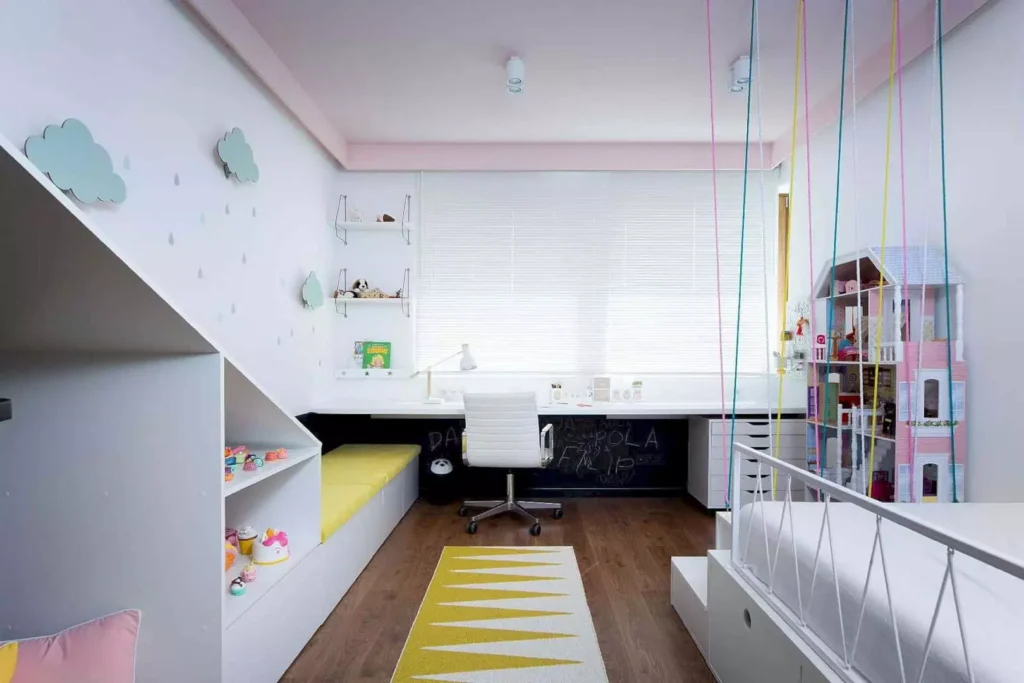 A bright and colorful children's bedroom with a built-in desk and shelving unit under a loft bed. Decorative clouds and raindrops adorn the walls, adding a playful touch to the room's design.