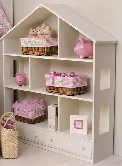 A white house-shaped bookshelf with open shelves and drawers. Pink and white gingham-patterned baskets and piggy banks adorn the shelves, adding a charming touch to the room's decor.