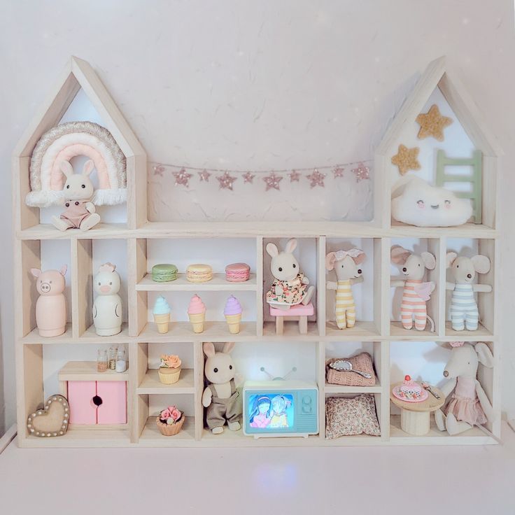 An adorable wooden shelving unit decorated with various cute plush toys, miniature furniture, and decorative items such as ice cream cones, macarons, and stars.