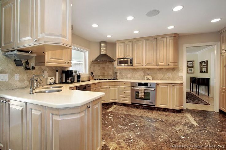 "Spacious kitchen with light wood cabinets, marble countertops, stainless steel appliances, and tiled backsplash"