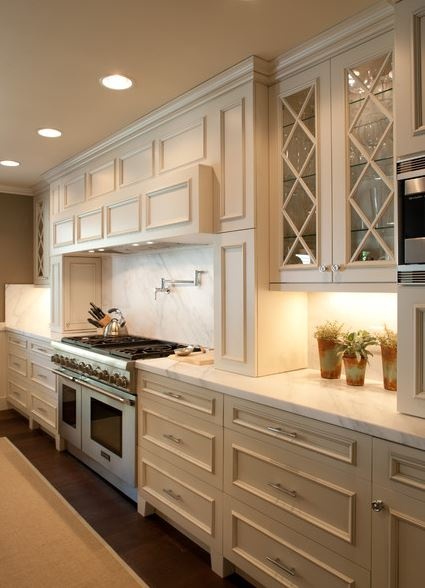 "Classic kitchen with cream-colored cabinets, marble countertops, glass door cabinets, and potted plants on the countertop"